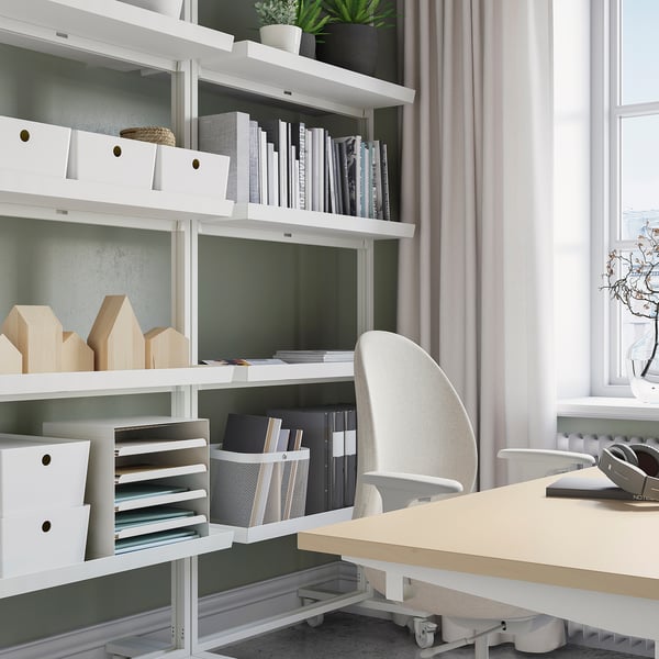 Modern home office with MITTZON white shelving, beige desk, and grey chair. Shelves hold organized files, books, and decor.