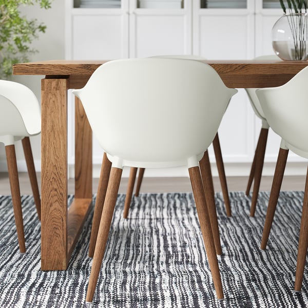 Wood dining table with white chairs; natural wood grain, comfortable seating.