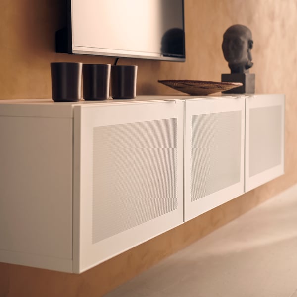 White modern cabinet with metal mesh doors; sleek handles; decor items on top.