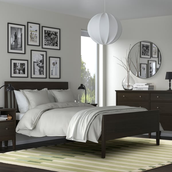 Modern bedroom with rug, wooden bed, globe lamp, photo wall.