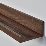 Dark wood shelf mounted on wall. Grooved edge for holding frames.