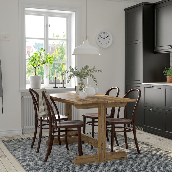 Cozy dining area with wooden table, chairs, pendant lamp, and decorative vase.
