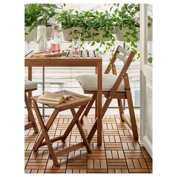 Wooden balcony set with light cushions, plants, and books.