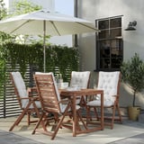 Modern patio set with wooden table, four folding chairs, white cushions, and a large beige umbrella.
