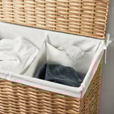 Laundry basket with open lid reveals separated white and blue clothes in a white inner bag, woven from natural willow.
