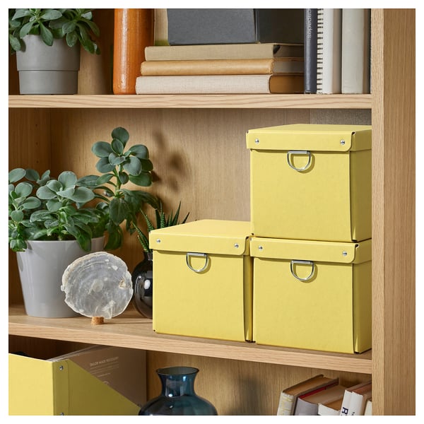 Wooden shelf with three yellow NIMM organizer boxes, plants, and books.