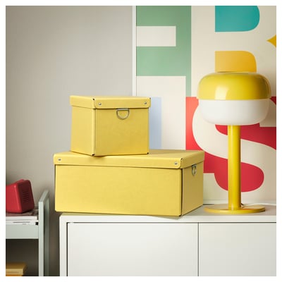 Two stackable yellow NIMM boxes on white cabinet, right beside a yellow lamp, ideal for organizing small items.
