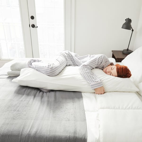 Person sleeps peacefully on soft, breathable cotton pillowcase in cozy, minimalist bedroom.