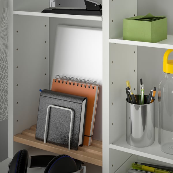 Shelf with notebooks, pens, and water bottle. Organized work or study space.