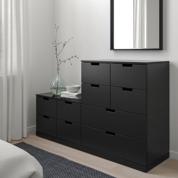 Black NORDLI chest with 6 drawers in minimalist bedroom.