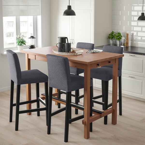 Small modern wood bar set with four grey cushioned stools beside a kitchen window.