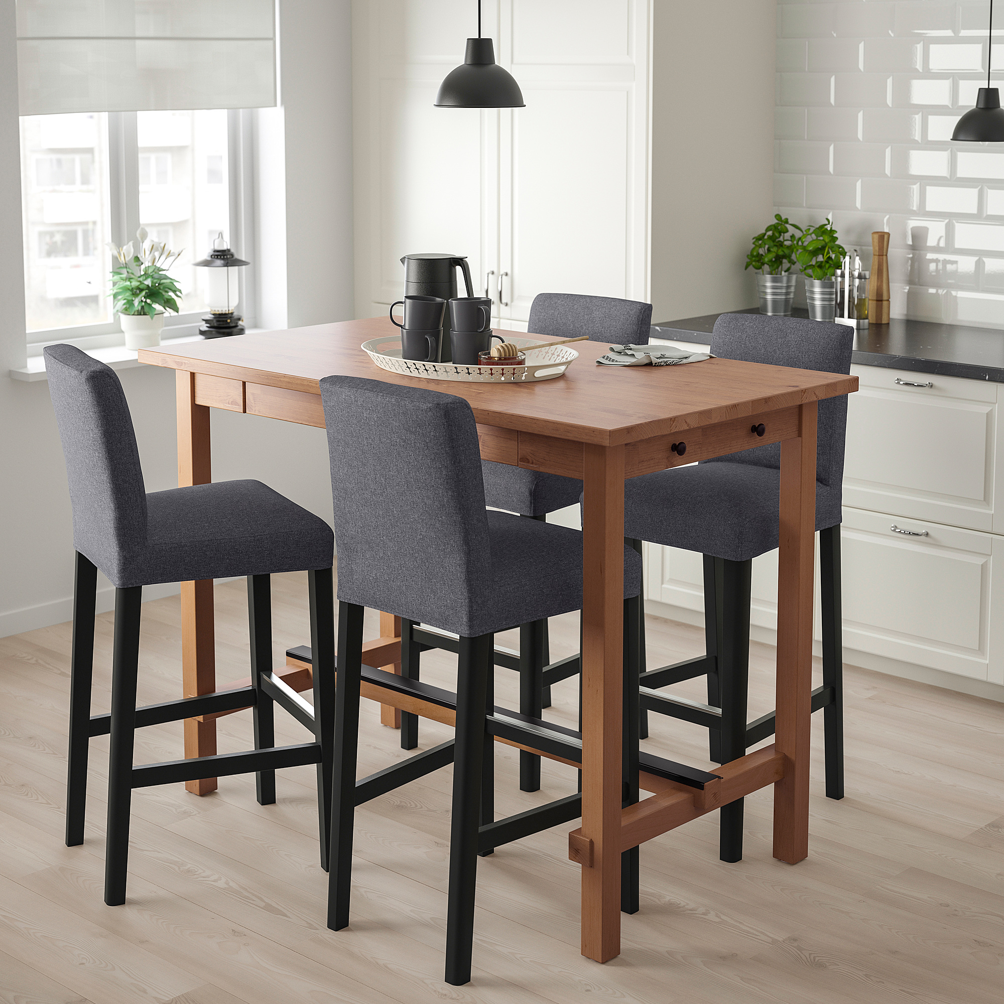 Small modern wood bar set with four grey cushioned stools beside a kitchen window.