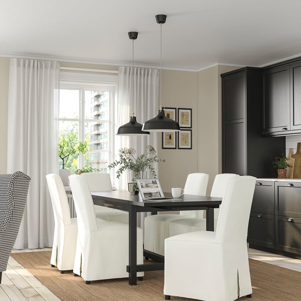 Modern dining area with NORDVIKEN chairs around extendable table, black pendant lights, window, dark kitchen, patterned chair.