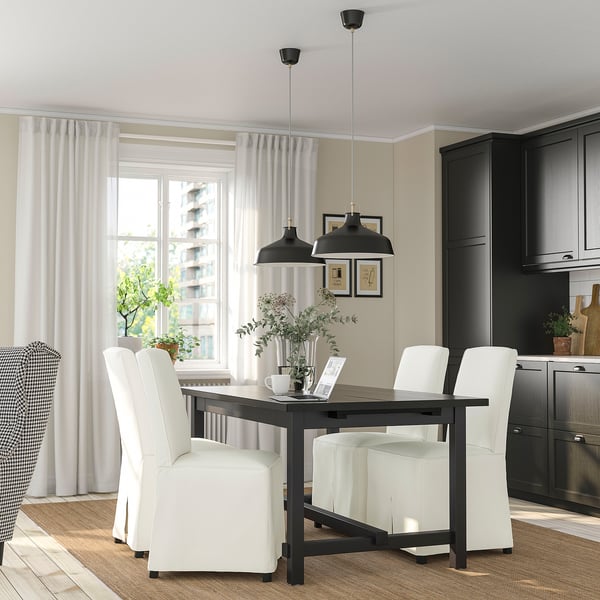 Modern dining room with extendable table, white chairs, large window, plant.