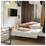 Modern bedroom featuring a white folding bed with pink accents, a flat-screen tv, wooden wardrobe, and colorful wall art.