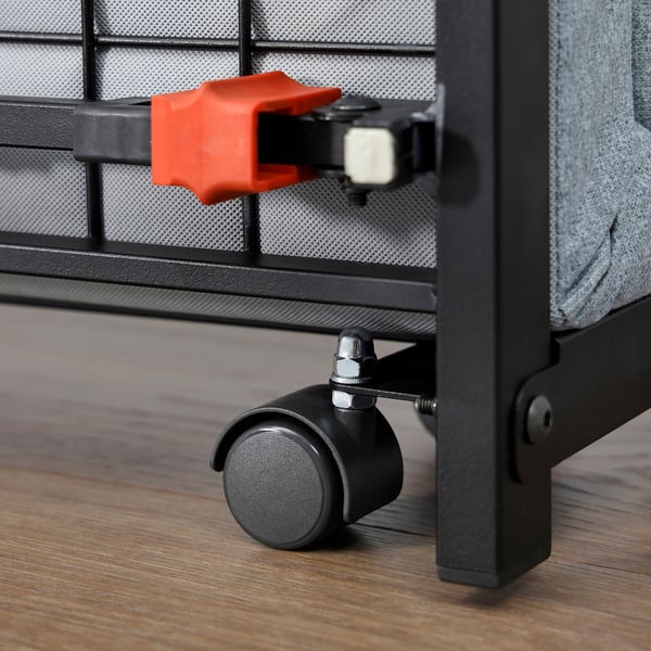 A rolling bed with a red lever, black casters, and metal mesh frame. Easy to roll and lock in place, perfect for guest use.