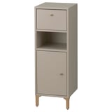 A NORSÄLVEN bathroom storage cabinet in beige. It a drawer, a door, and an open shelf. The cabinet has a slim design with wooden legs.