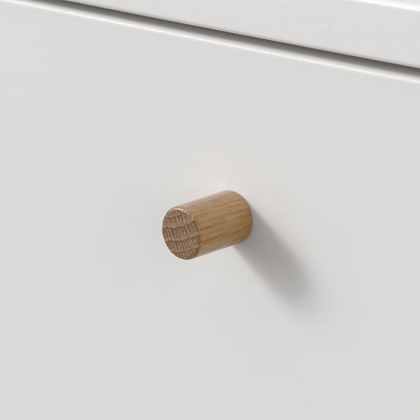 Cylindrical wooden knobs on white cabinet, suggesting sturdy and elegant construction.