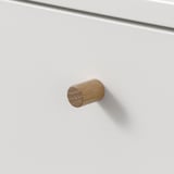 Cylindrical wooden knobs on white cabinet, suggesting sturdy and elegant construction.