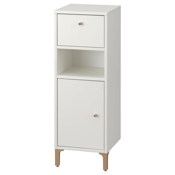 This image shows a white NORSÄLVEN bathroom cabinet with a drawer, door, and shelves for storage. It has wooden legs and a clean, minimalist design.