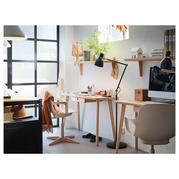 Minimalist home office with wooden desk, lamp, computer, plants. Natural light.