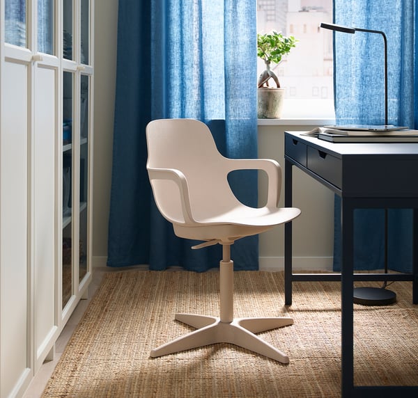 Modern home office with white ODGER swivel chair, black desk, blue curtains, and natural rug.