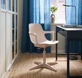 Modern home office with white ODGER swivel chair, black desk, blue curtains, and natural rug.