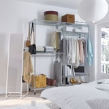 Bedroom with silver shelving, mirror, bed, and light fixture.