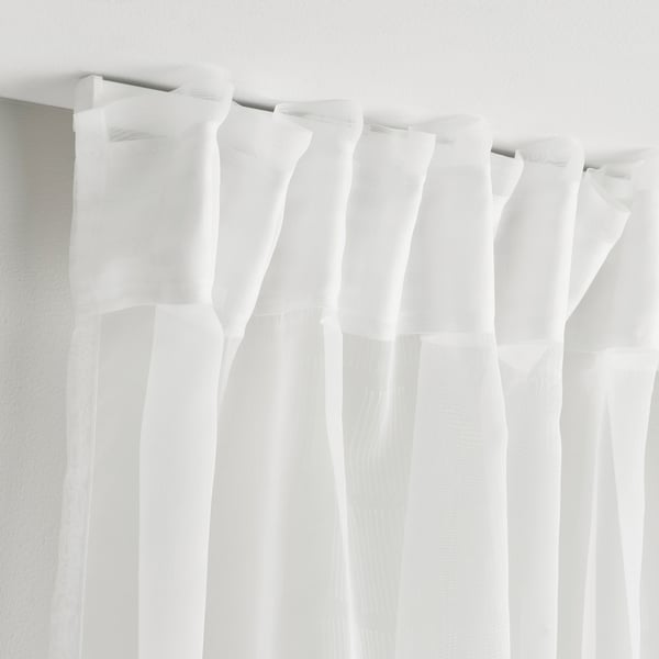 White curtains with subtle pattern hang neatly, diffusing light for privacy.