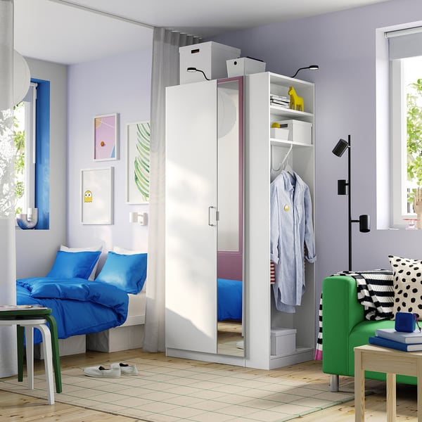 Modern bedroom with white PAX wardrobe, blue bed linens, green chair, wooden floor.