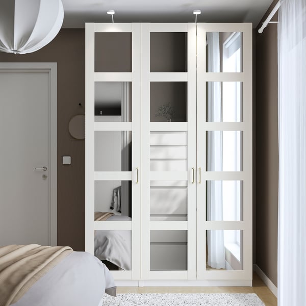 White PAX wardrobe with mirrored doors, minimalist design, large beside bed.