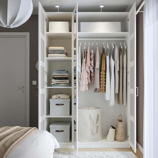 Open white PAX wardrobe showing clothes, folded items, and storage boxes. Tall, rectangular, with multiple shelves and hanging space.