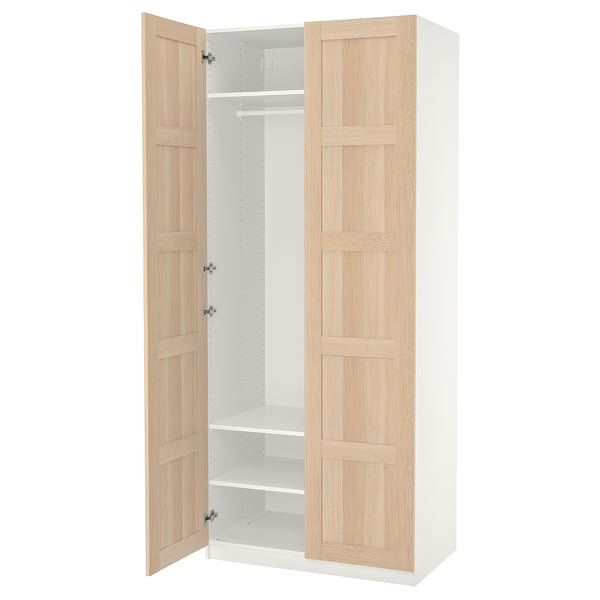 An open wooden wardrobe named PAX with light oak doors and white interior.