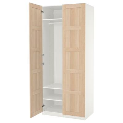 An open wooden wardrobe named PAX with light oak doors and white interior.