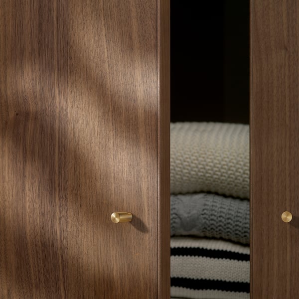 Wooden doors with shiny gold handles; folded blankets inside visible crack.