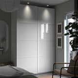 Modern bedroom with white PAX wardrobe, glass doors, and integrated lighting.