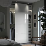 Modern bedroom with white PAX wardrobe, glass doors, and organized shelves.