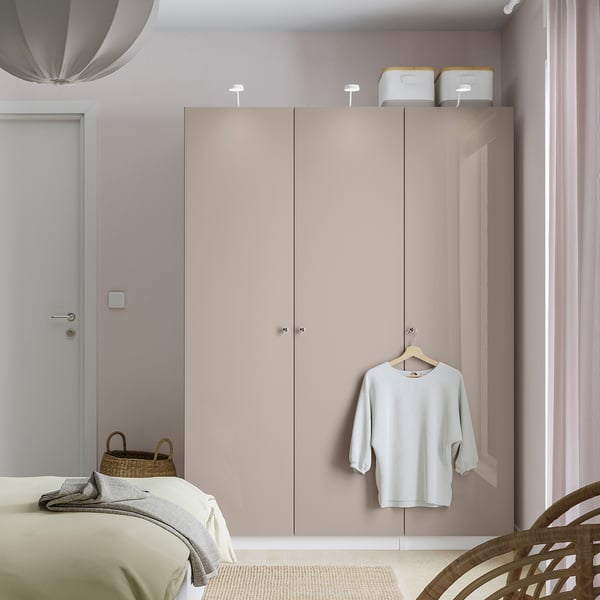 Modern bedroom with large beige PAX wardrobe, white shirt hanging, bed with grey blanket, and basket on floor.