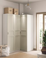 Modern corner wardrobe with beige doors and green interior, featuring top storage boxes and a pendant light.
