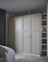 Modern bedroom with large gray PAX wardrobe, wide doors, shelves, and lighting.