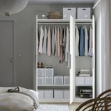 A modern open closet displaying clothes and storage bins, demonstrating organizational functionality.