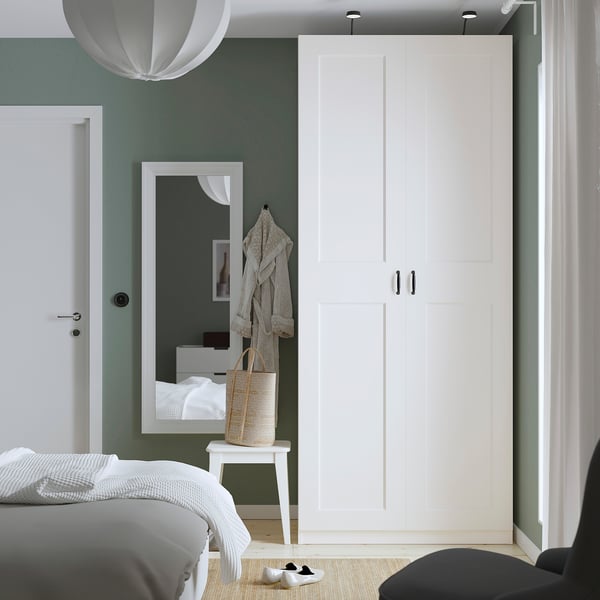 Modern bedroom with large white PAX wardrobe, tall mirror, and sage green walls.