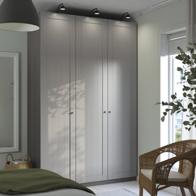 Modern bedroom with gray PAX wardrobe, spotlights, window, wicker chair, and lamp.
