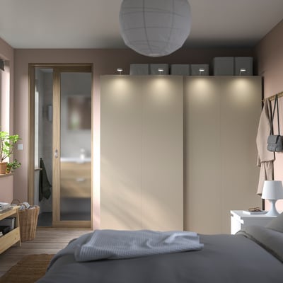Modern bedroom a PAX wardrobe with sliding doors, neutral tones, gray bedding, and a cozy atmosphere.