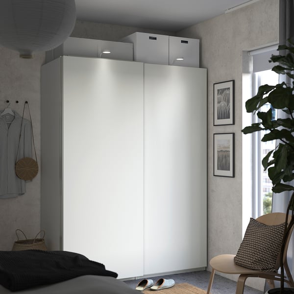 Minimalist bedroom with PAX wardrobe, chair, and plant.