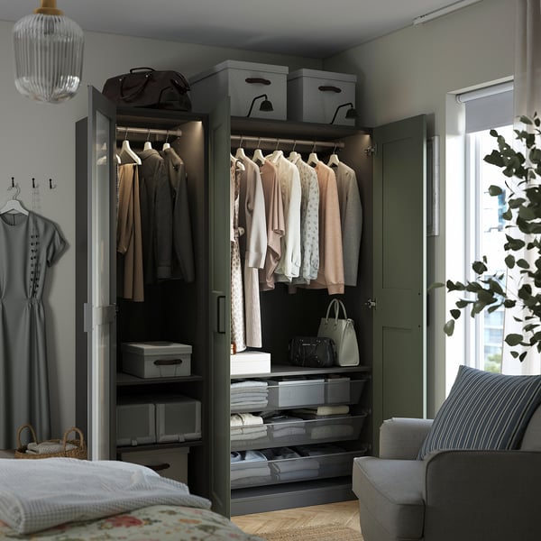 Open wardrobe with clothes, bags, and folded fabrics. Grey colour, organised with boxes and shelves.