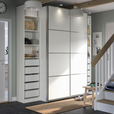 Modern white PAX closet, sliding doors, tall units, drawers, shelves, stylish design.
