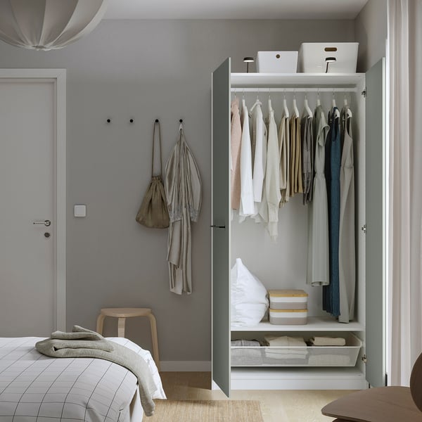 Modern wardrobe with hangers, blankets, and storage bins. Coats on hooks beside a door.