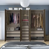 Modern open closet with hangers, shelves, bins, and drawers neatly organizing clothes and accessories against blue wall.