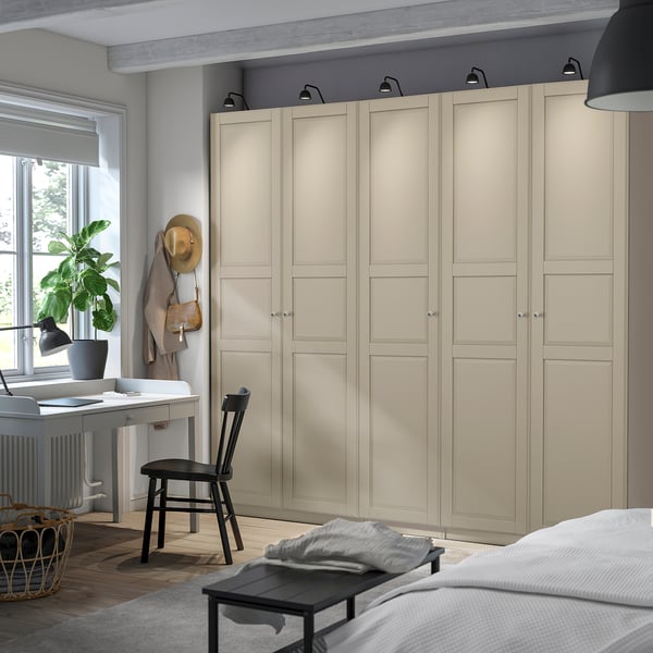 Cozy room with large light beige PAX wardrobe, dark wood desk, chair, and basket.